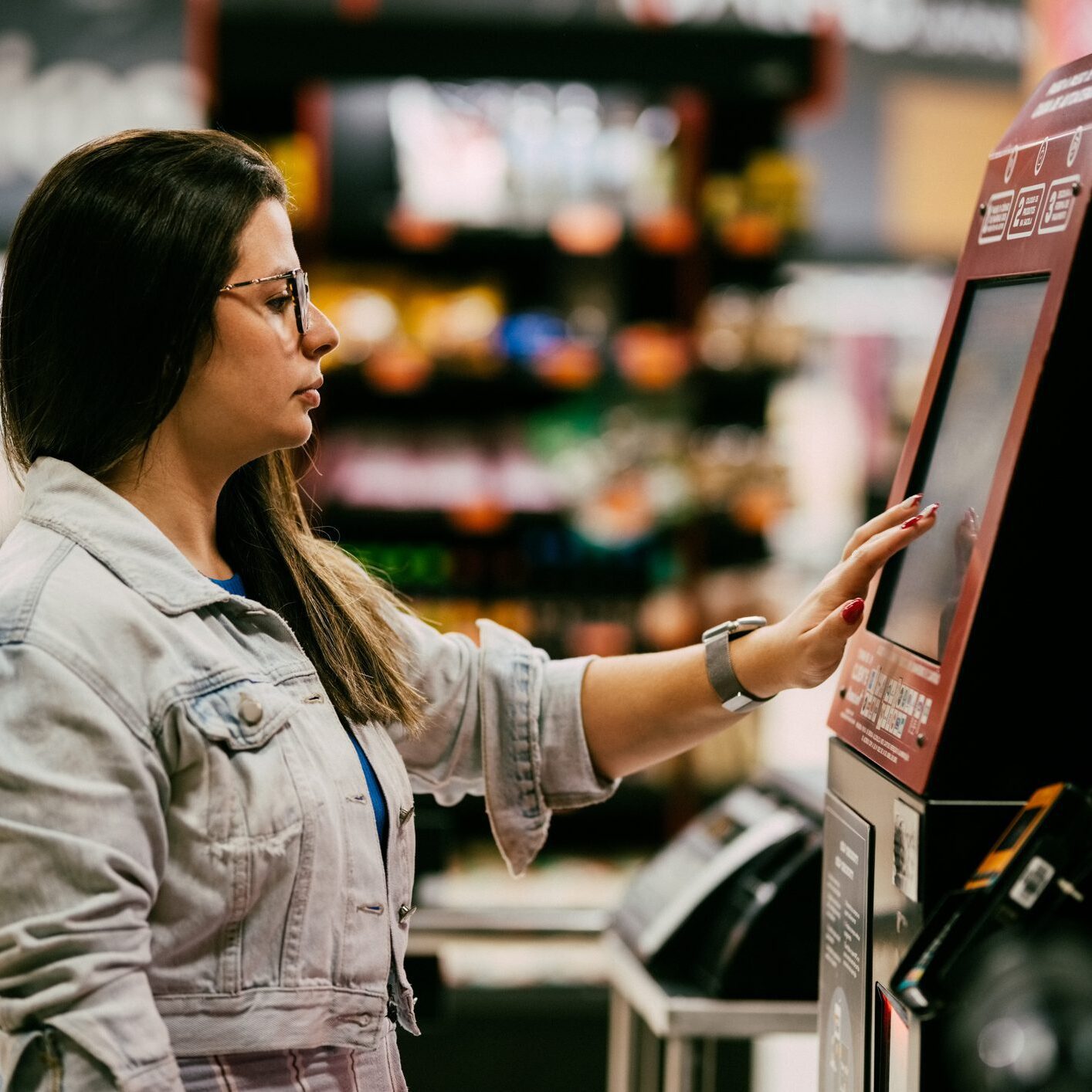 Woman using a self-checkout machine in store.