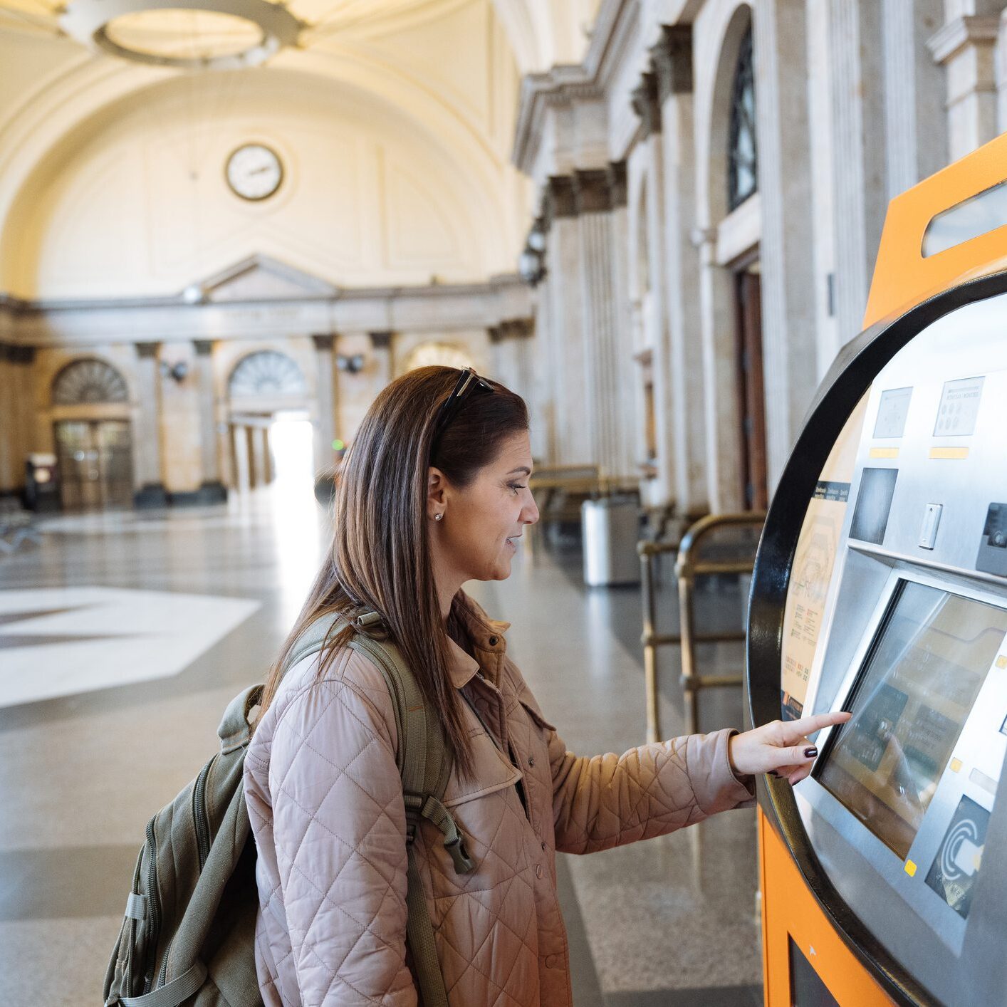 Woman using ticket machine in train station.